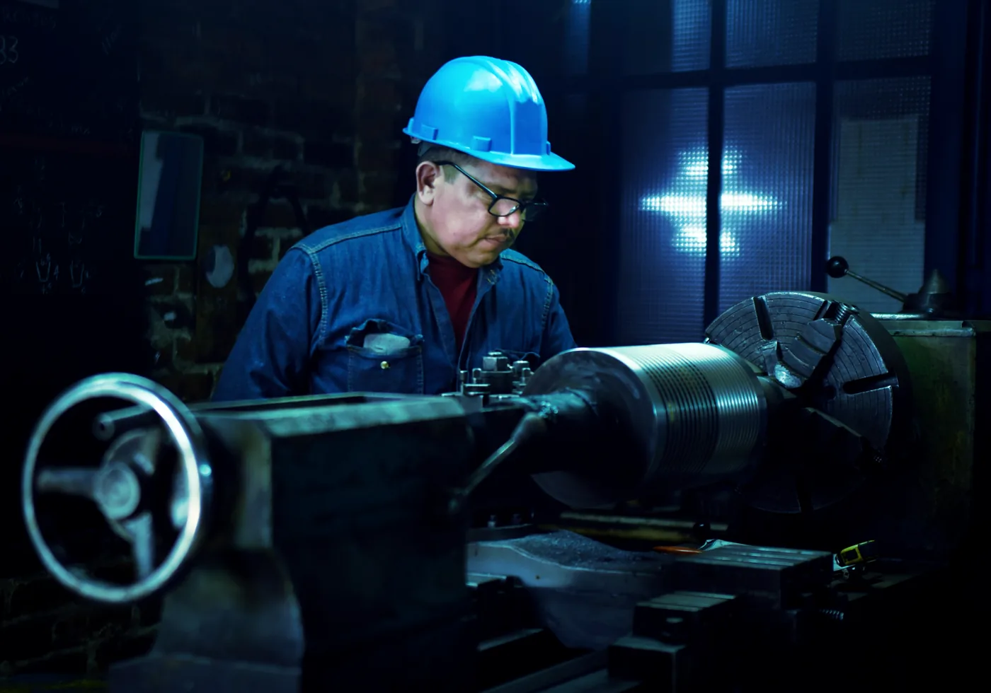 Machinist in a hard hat and safety glasses operating a lathe
